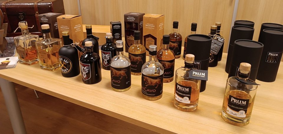 Aufgereihte Whiskyflaschen und Probiergläser während eines Tastings
